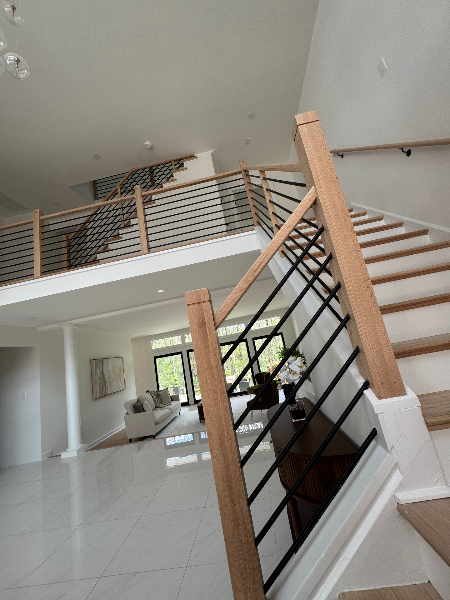 Grand foyer staircase with white oak rails and black metal balusters