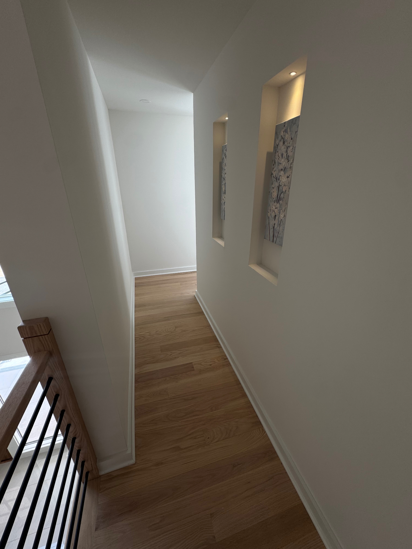 Upstairs hallway with recessed wall niches and hardwood floors