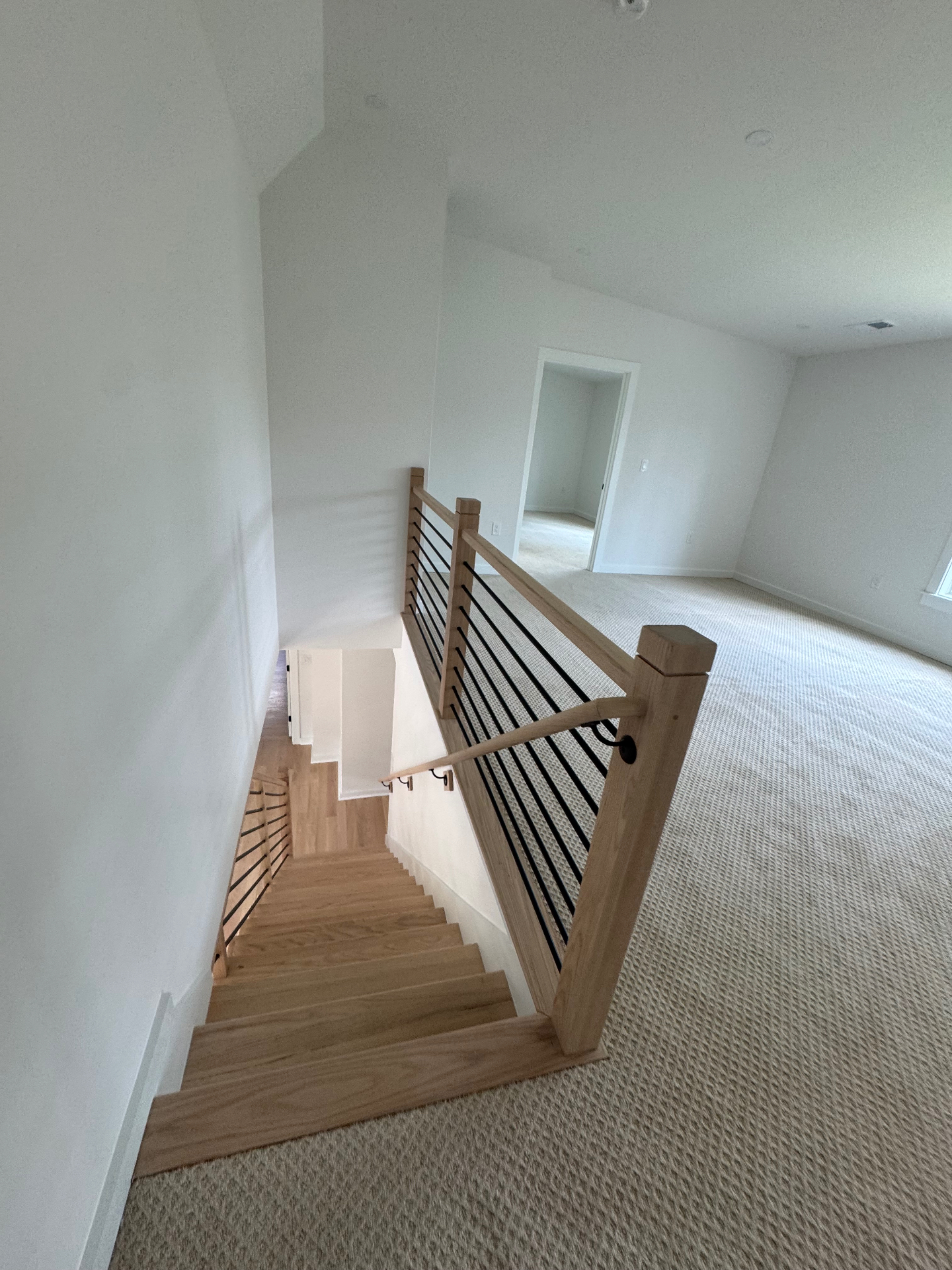 Modern staircase with horizontal black railing and white oak trim